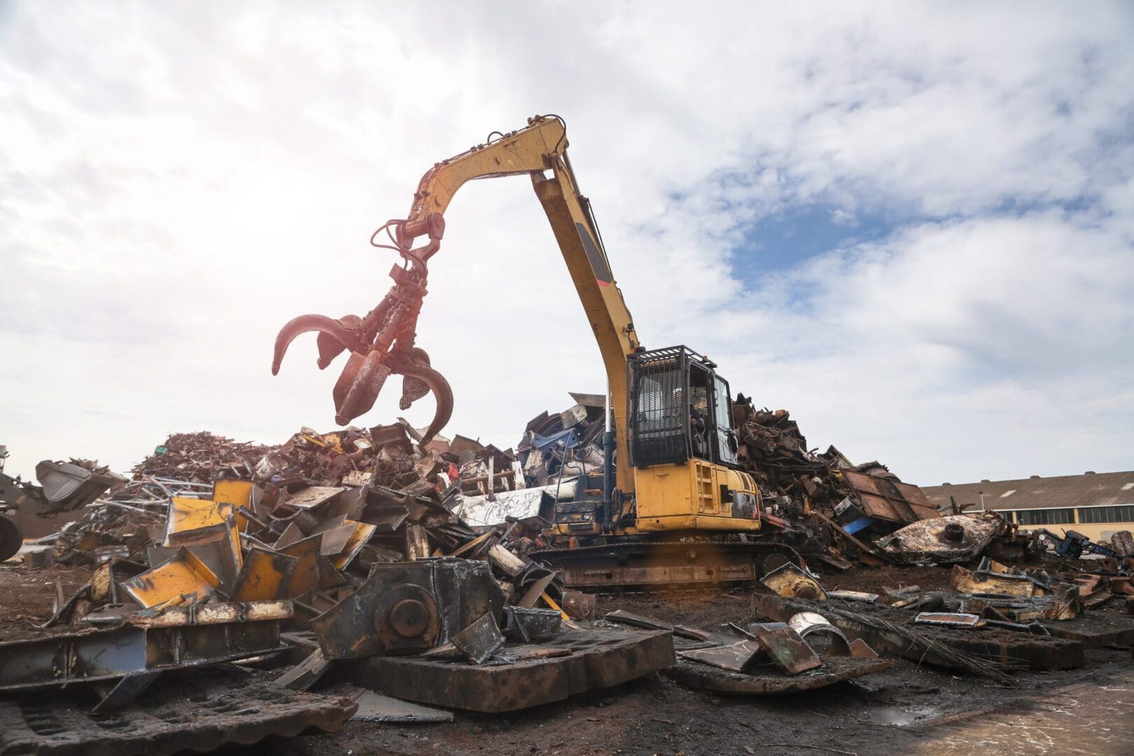 Excavator moving metal scrap in junkyard.