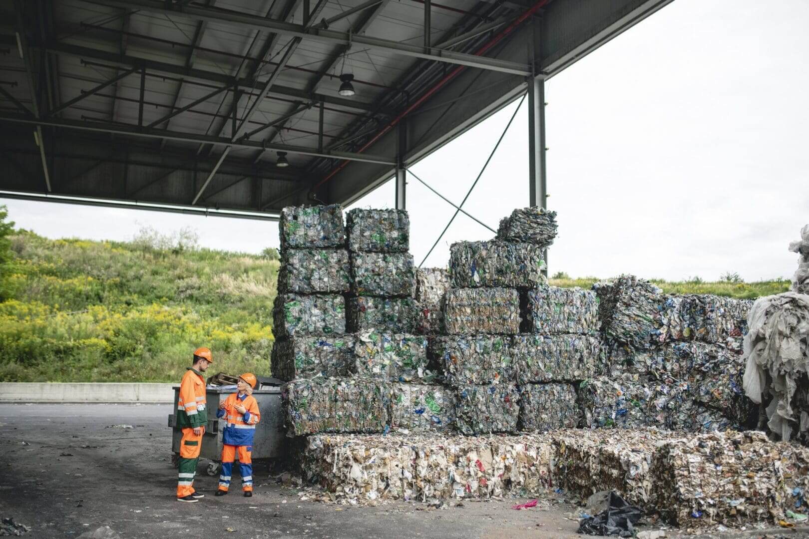 Workers standing near stacked recycling bales.