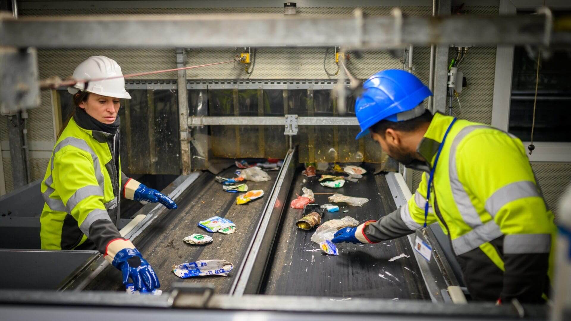 Workers sorting recyclables on conveyor belt.