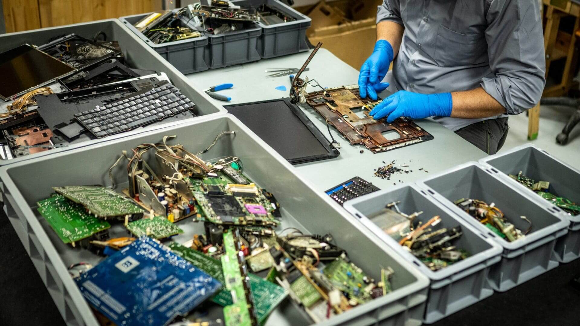 Technician disassembling electronics on a workbench.
