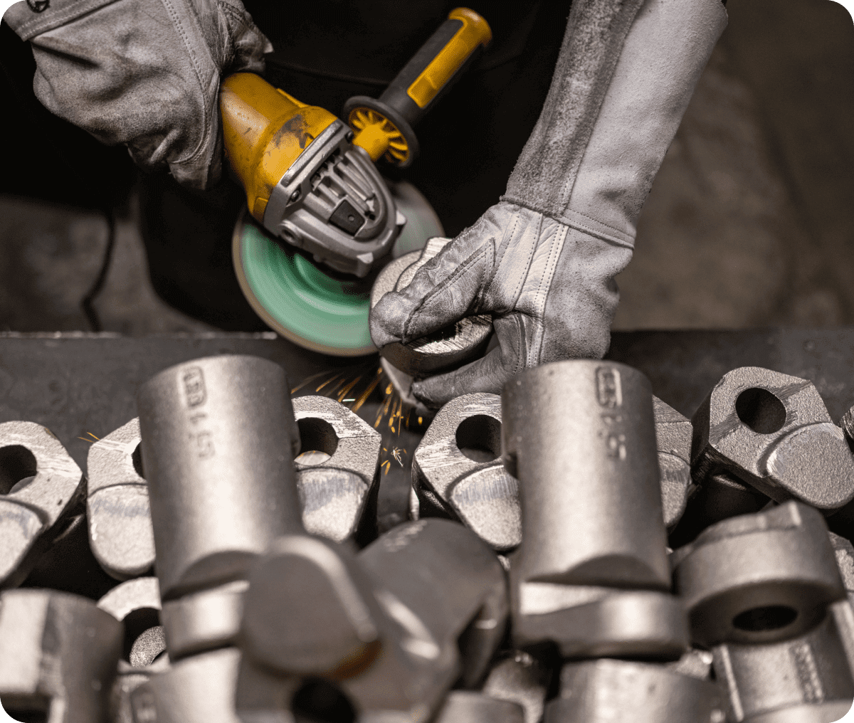 Worker using grinder on metal parts.